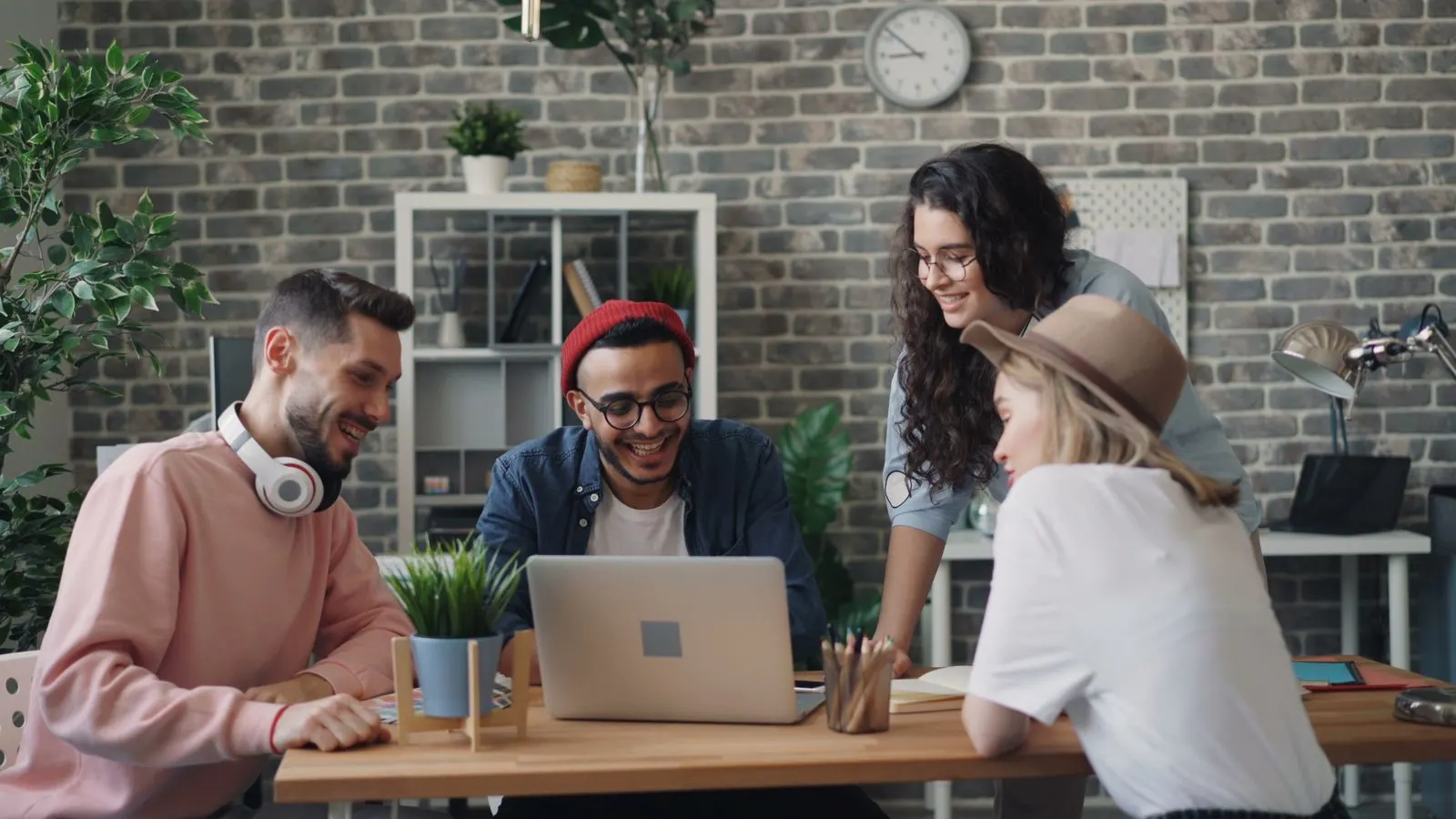 A colleague explaining an idea to a group gathered around a laptop.