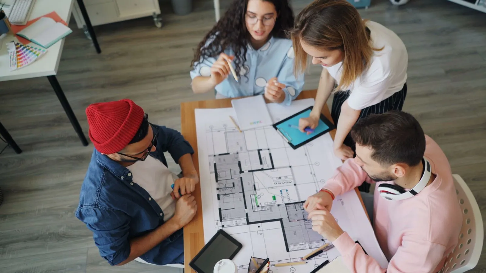 A project team working together over large plans spread across a table.