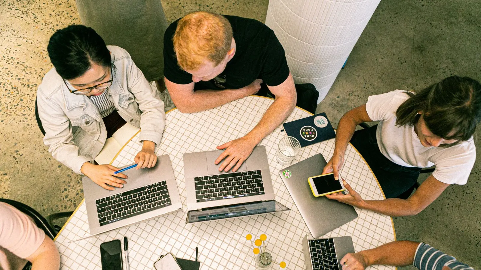 Overhead view of colleagues working together with laptops and handwritten notes.