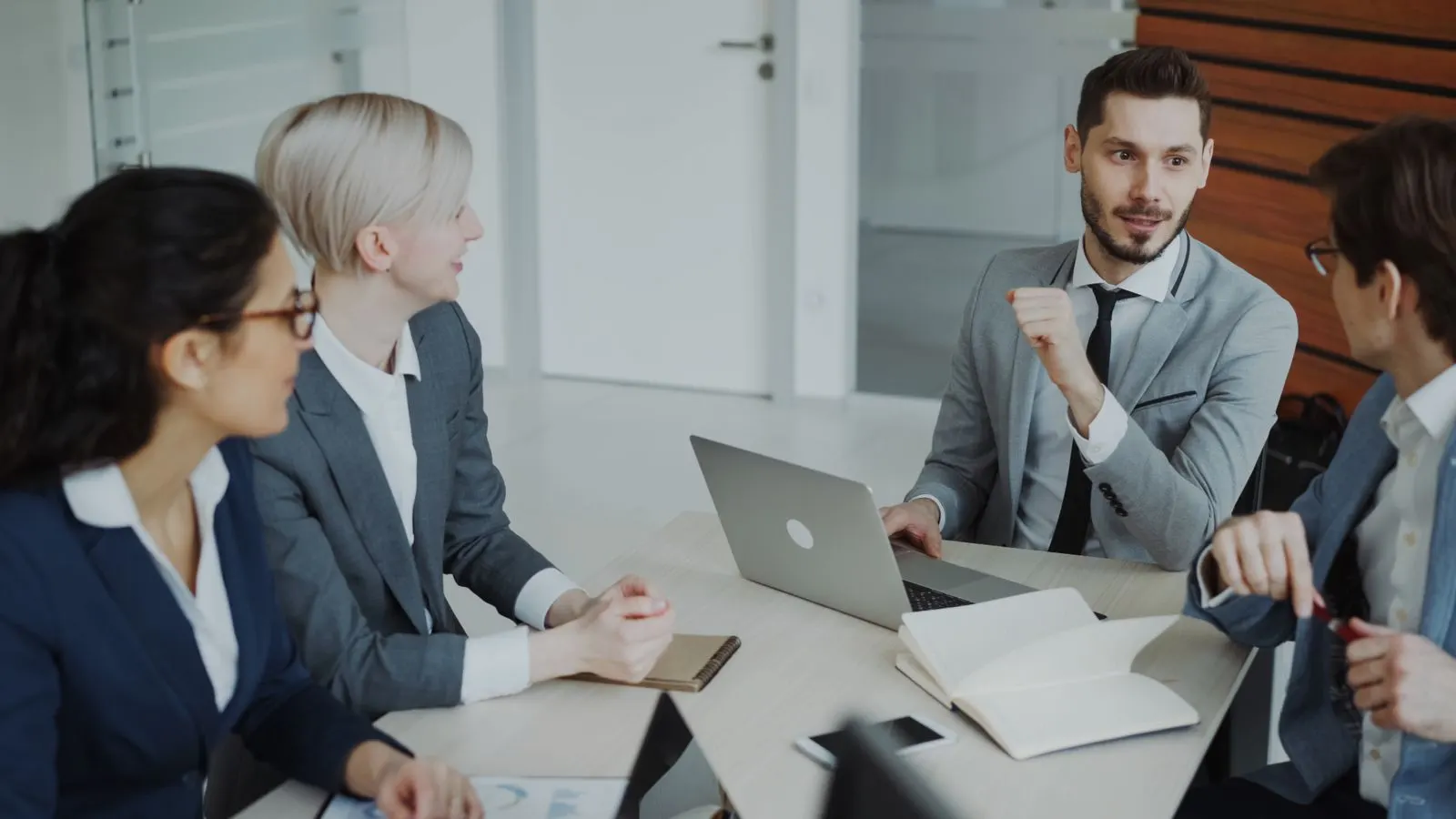 Colleagues comparing ideas and documents around a laptop in a meeting room.