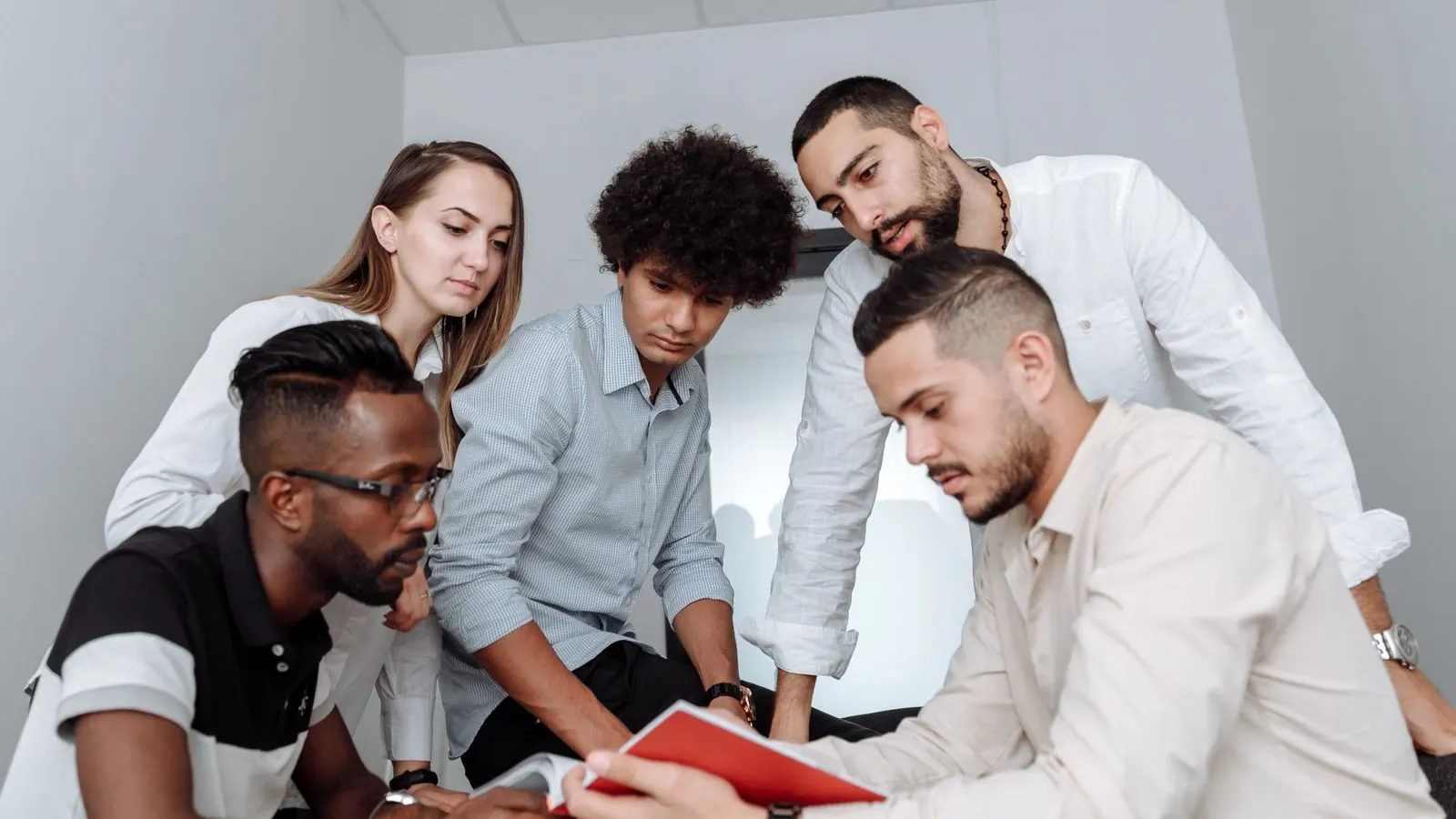 Five colleagues leaning over a shared tablet during a working discussion.