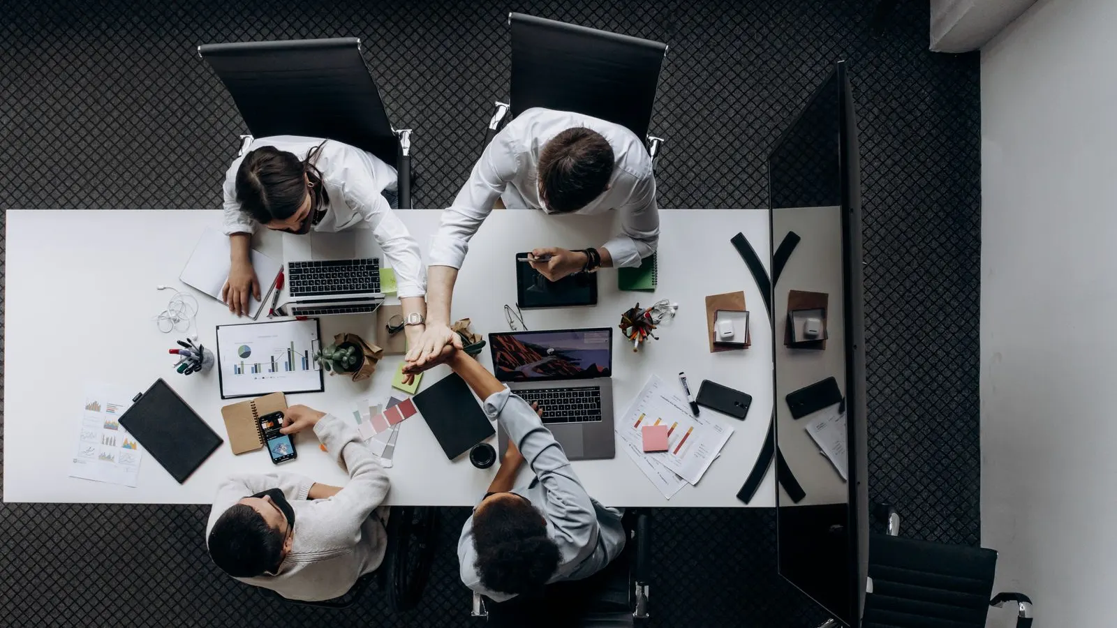 Overhead view of a group working around laptops, charts, and notes at a conference table.