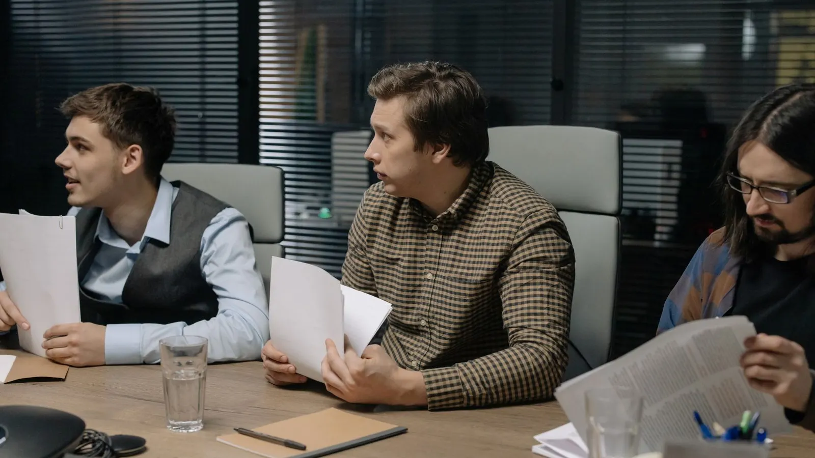 Colleagues reading and discussing papers together during an office meeting.