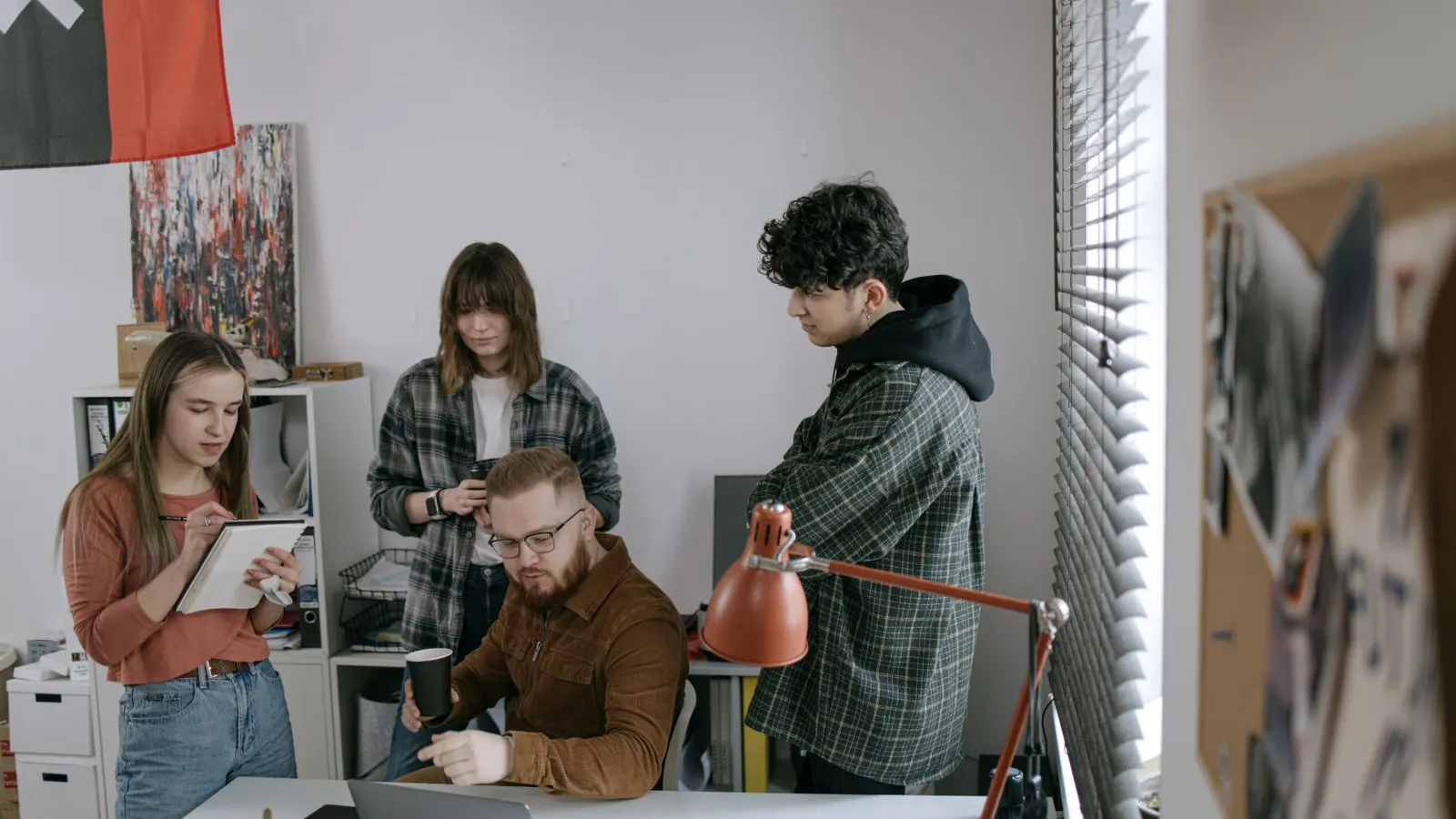 A project team gathered around a laptop and desktop monitor.