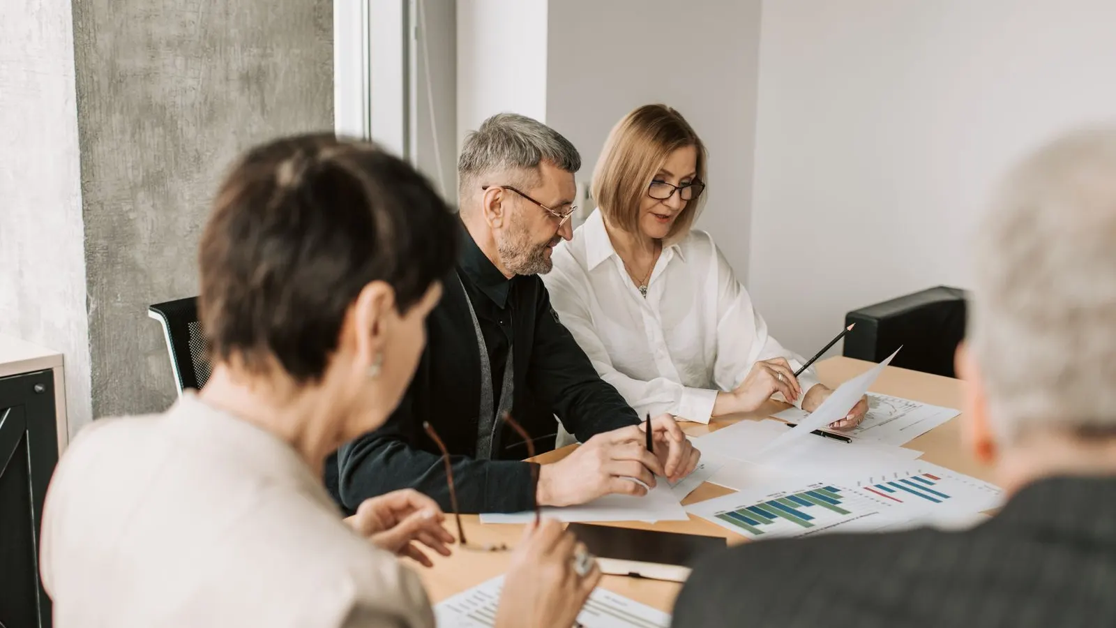 Business colleagues discussing printed charts and notes across a meeting table.