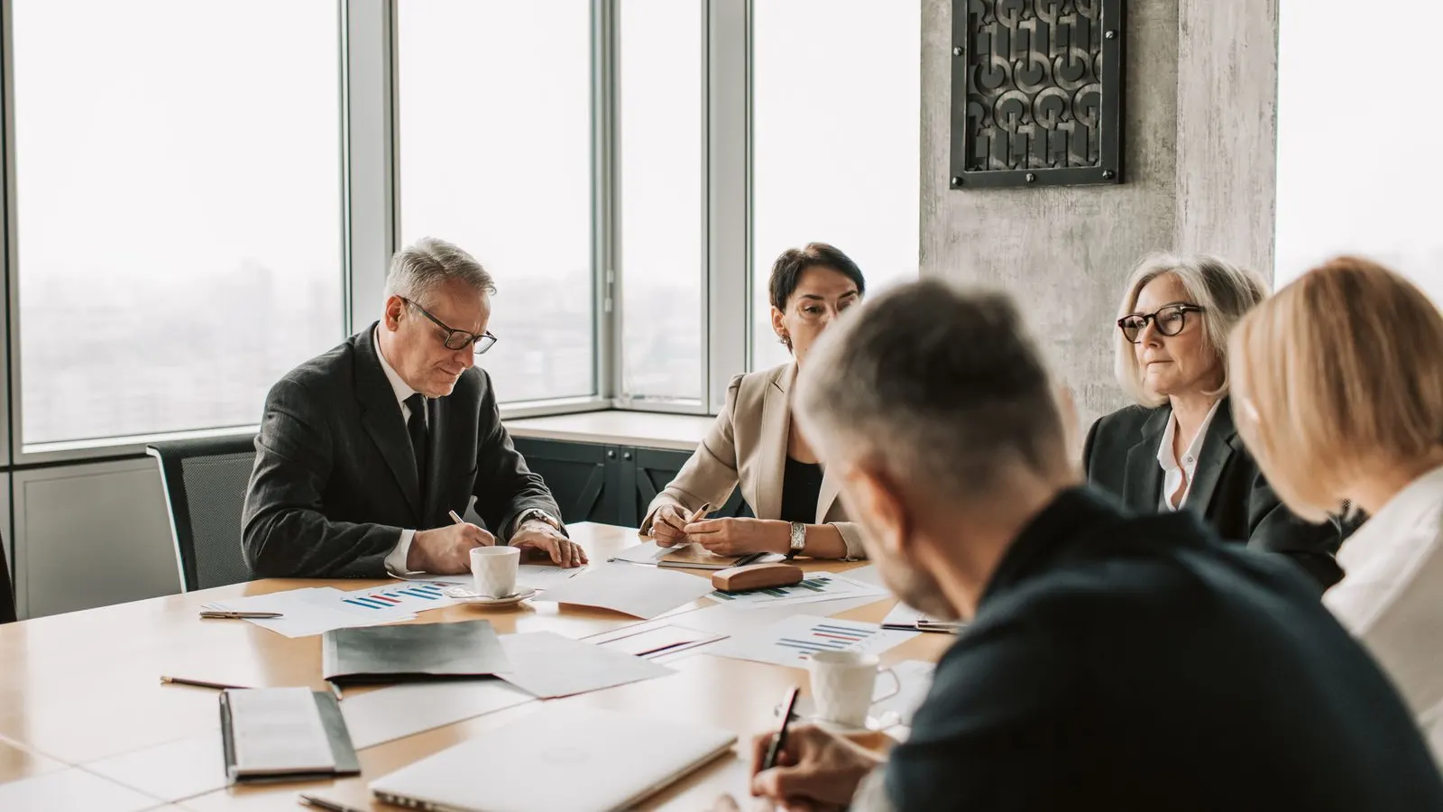 Business colleagues discussing documents around a sunlit conference table.