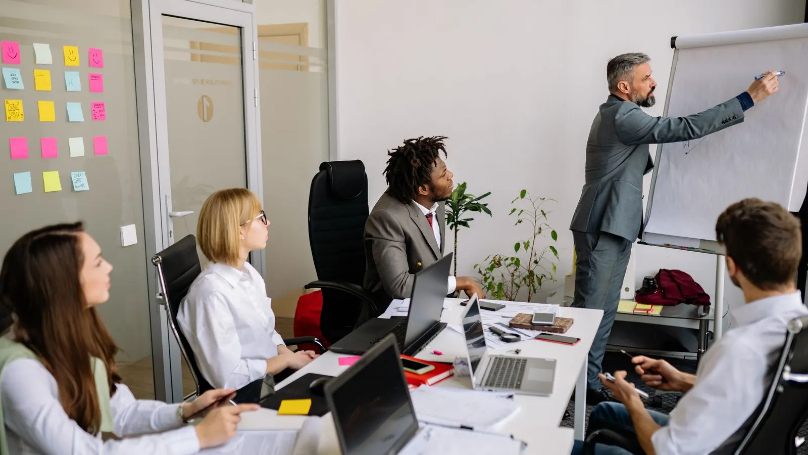 Colleagues taking part in a whiteboard discussion around a meeting table.