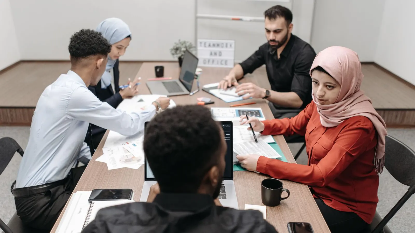 A team exchanging ideas over documents and a laptop at a conference table.